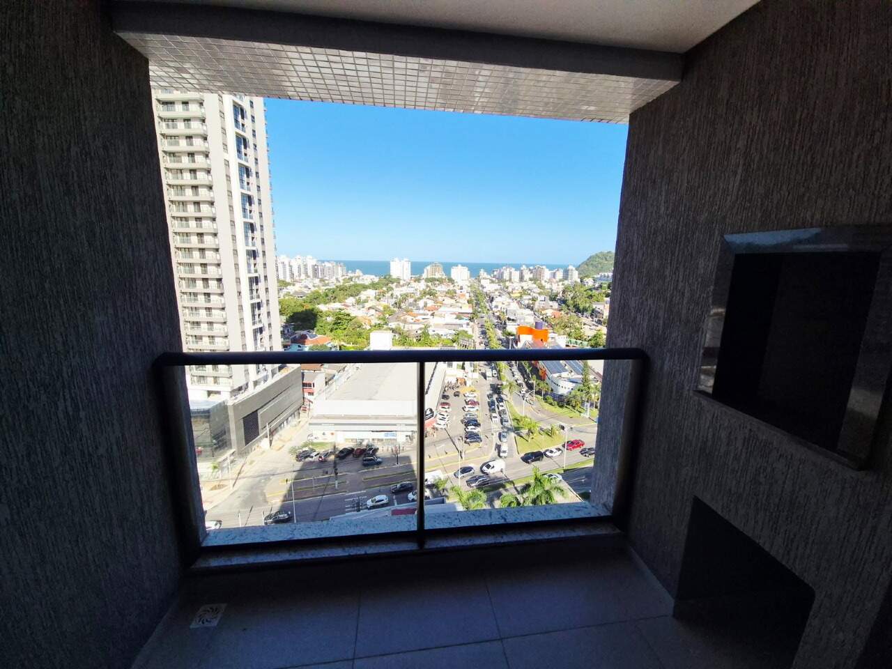 Apartamento à venda no Praia Brava: Sacada com churrasqueira e vista para o mar entre os prédios