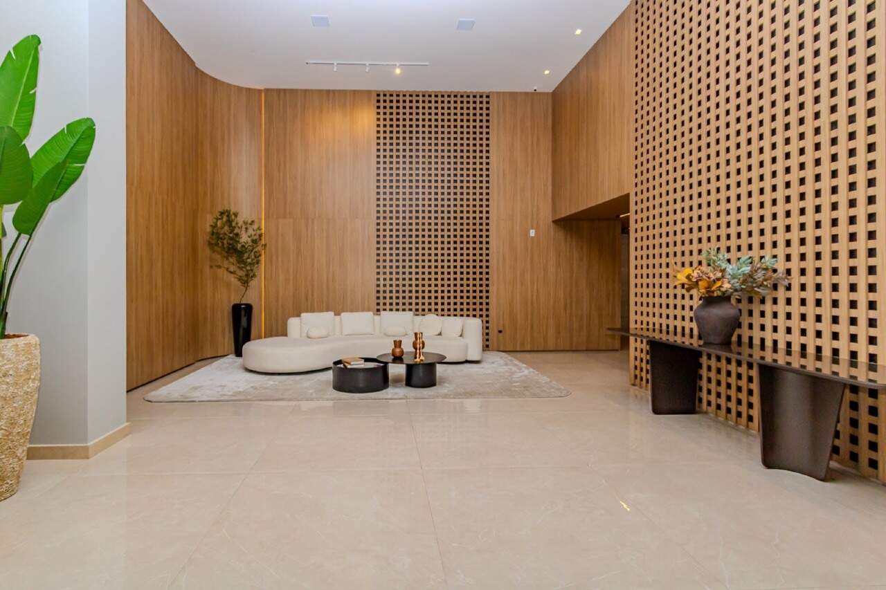 Apartamento à venda no Fazenda: Hall de entrada com painel de madeira e sofá curvo