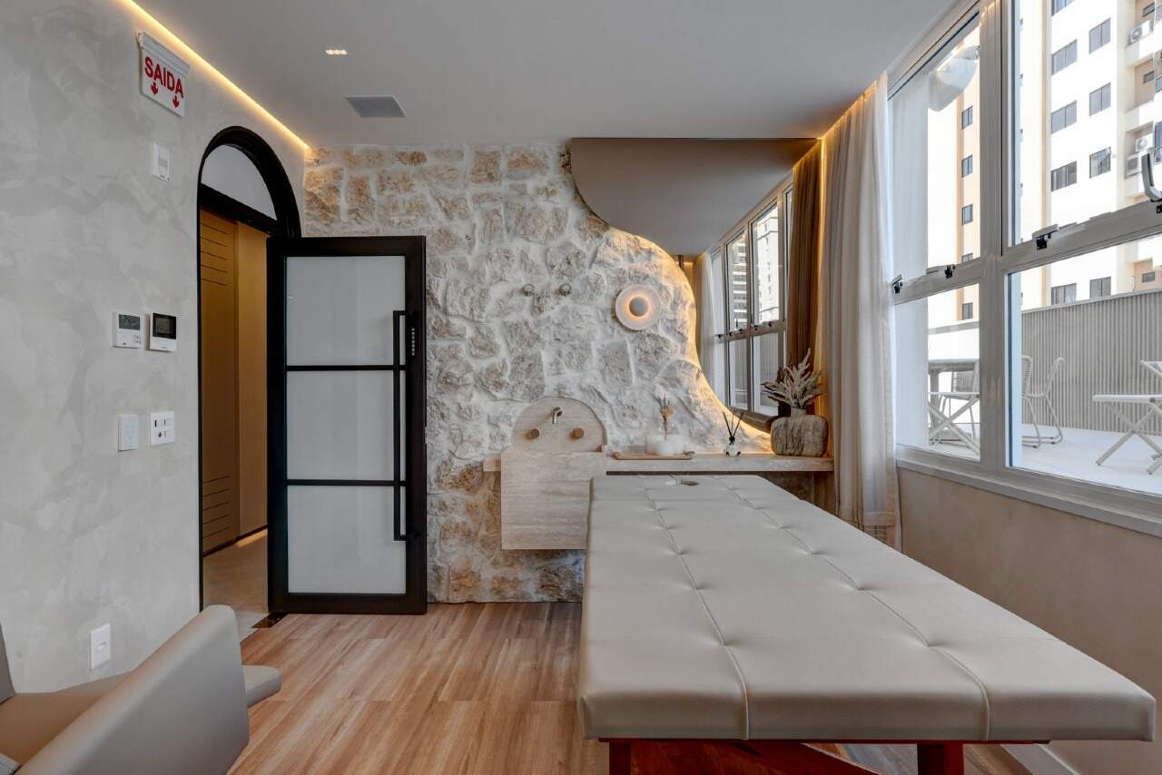 Apartamento à venda no Centro: Sala de massagem com maca e parede de pedra