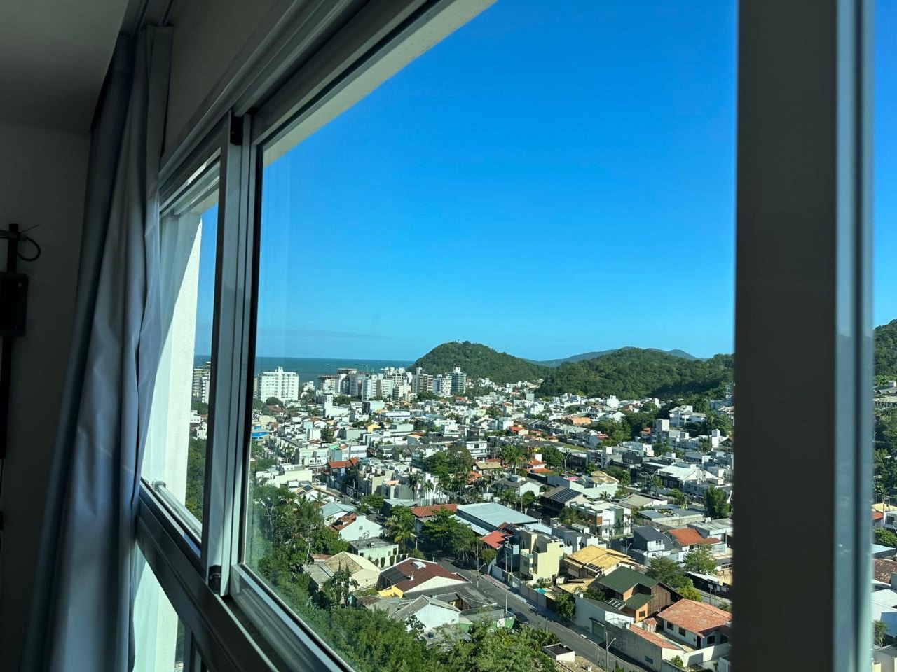 Apartamento à venda no Praia Brava: Vista da janela com o bairro, os morros e uma faixa de mar ao fundo