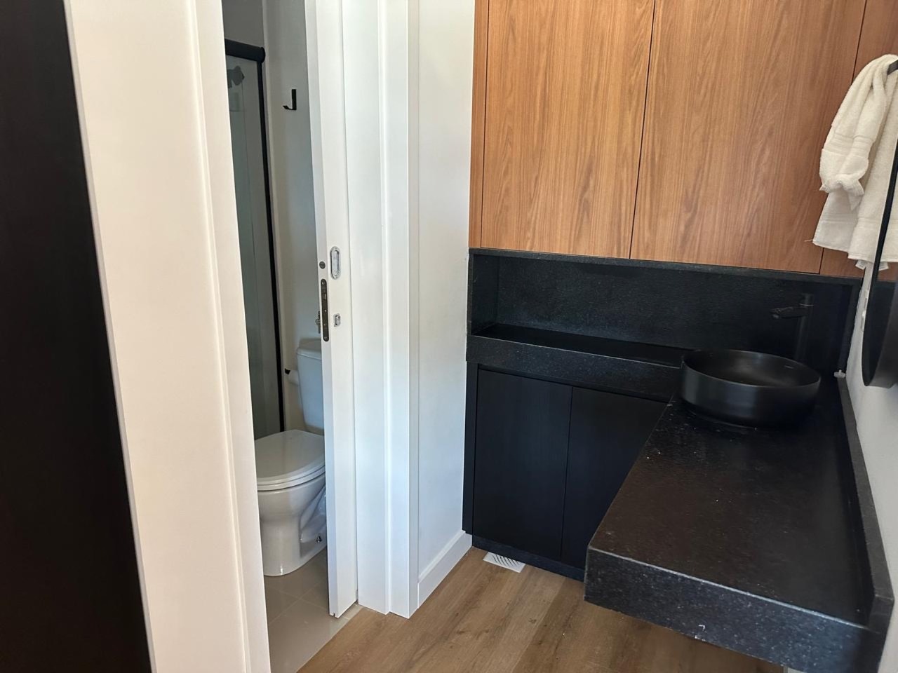 Apartamento à venda no Praia Brava: Banheiro com bancada escura e revestimento amadeirado