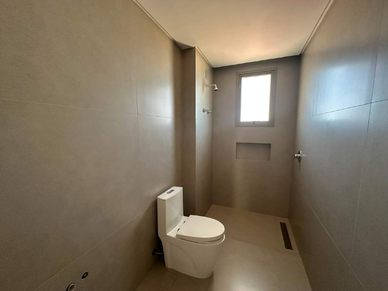 Apartamento à venda no Centro: Banheiro da suíte com revestimento cinza e nicho no box