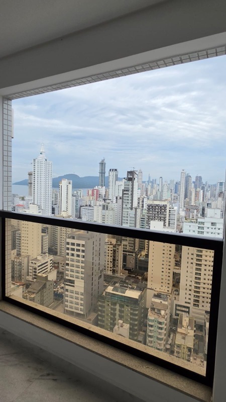 Apartamento à venda no Centro: Varanda com vista do Centro de Balneário Camboriú e faixa de mar entre os prédios